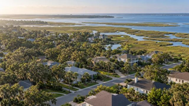 Illustrative aerial view of Northeast Florida-style homes, live oaks and a tidal marsh.